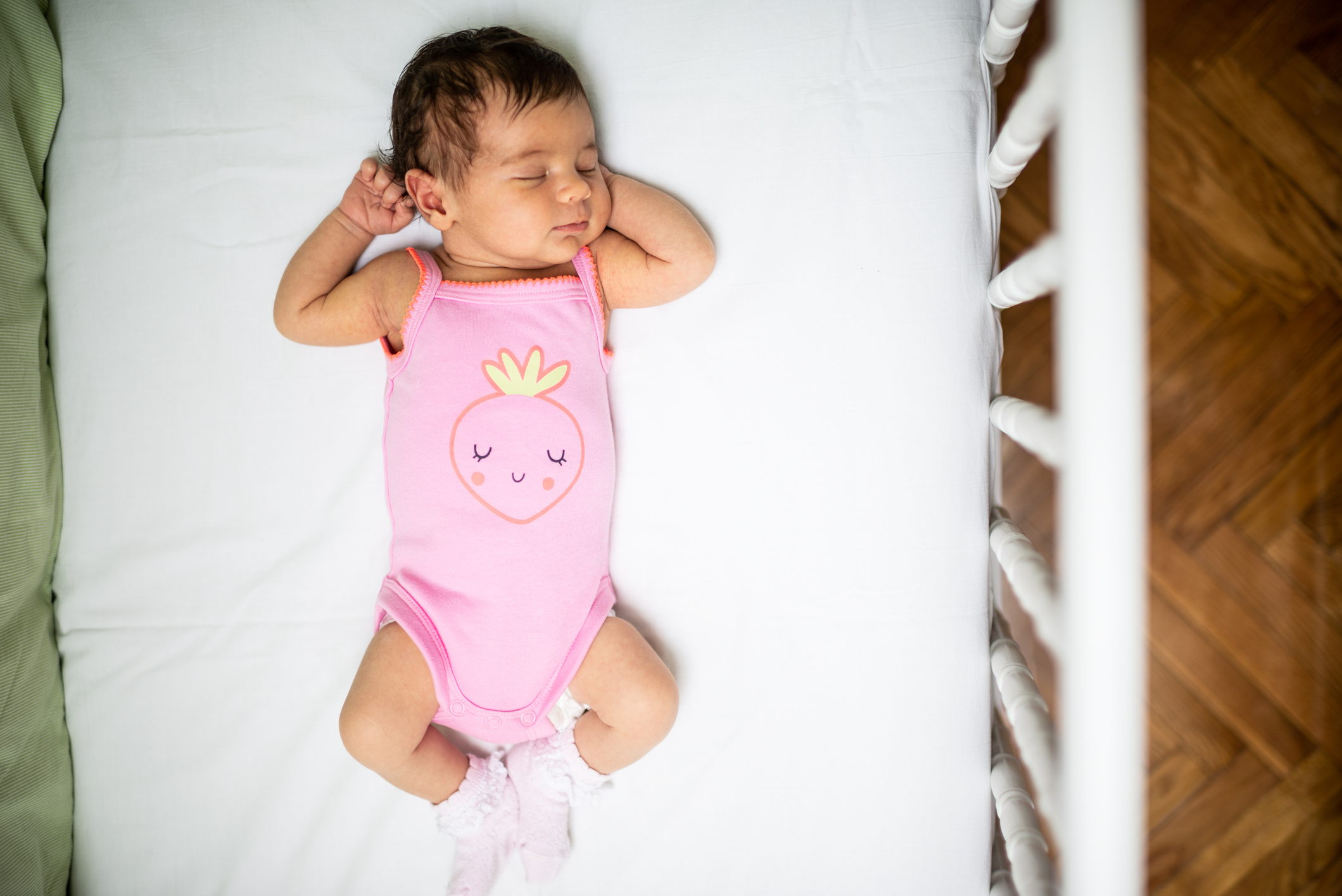 A top view of a baby asleep on her back in an empty crib for safe sleep