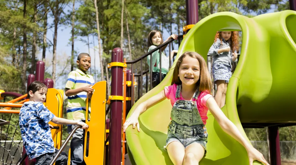 A group of school-age children happily plays together on a playground jungle gym