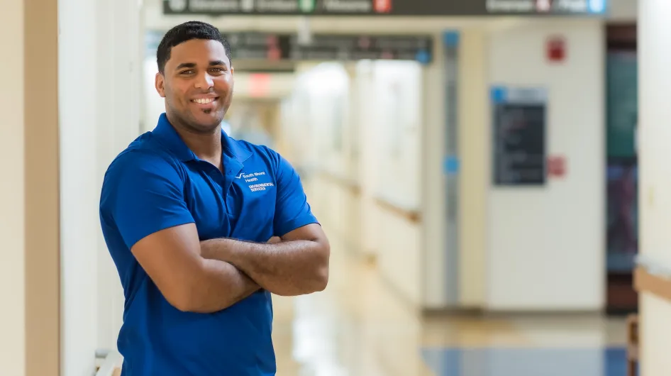 Kenio of South Shore Health's Environmental Services Team poses for a recruiting campaign photo in a hallway at South Shore Hospital.
