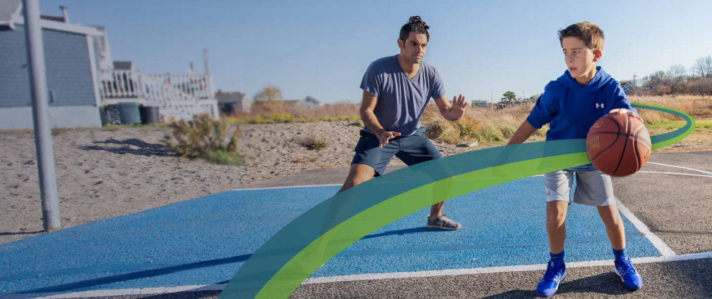 A man and child play basketball near the beach