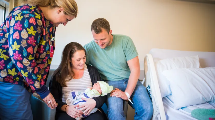 New mother and father holding child with nurse