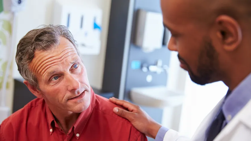 Doctor with hand on male patient's shoulder