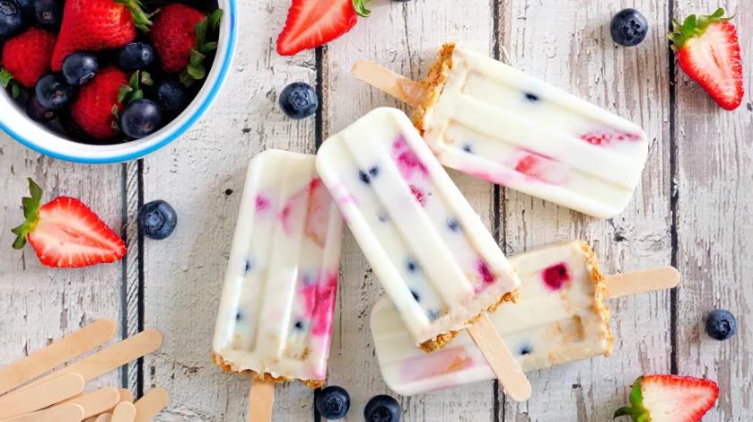 a bowl of fruit and a collection of colorful ice pops featuring blueberries, strawberries and other fruits