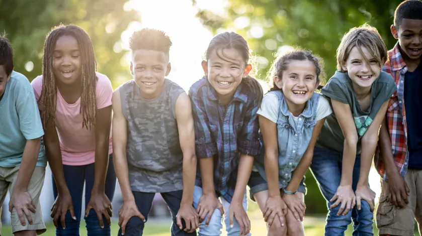 A group of kids poses smiling while playing outside in the summer