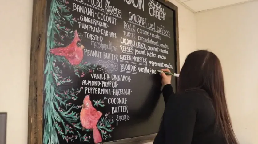 Maggie Russo puts the finishing touches on her chalkboard artwork in the Emerson Lobby Cafe at South Shore Hospital.
