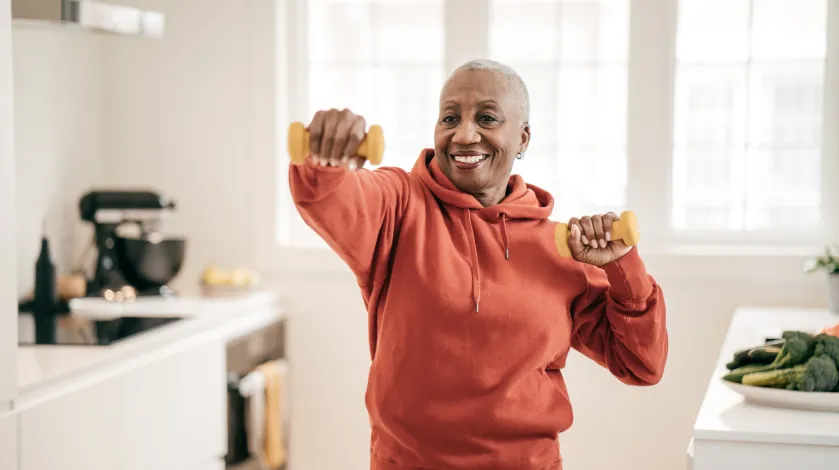 An older woman exercises in her home with hand weights