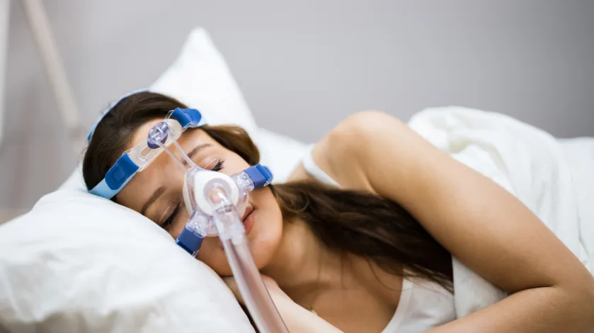 A woman sleeps while using a CPAP machine to help her breathing