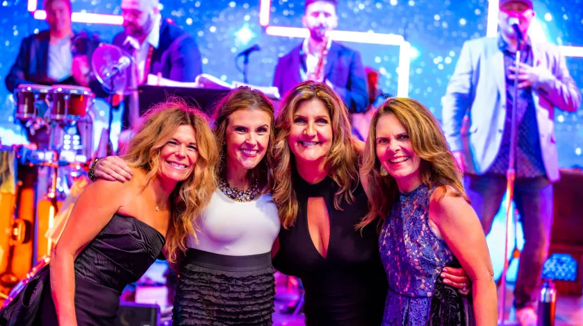 Group of ladies pose on the dance floor at the Moonlight & Miracles gala