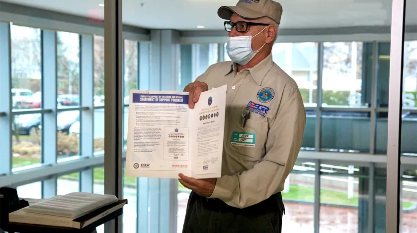 Retired Army First Sergeant John Bourne presents the Patriot Award to South Shore Health in November 2021.