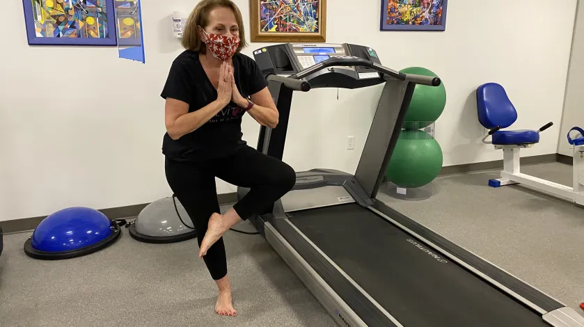 Terri Raymond balances on one leg in an exercise class