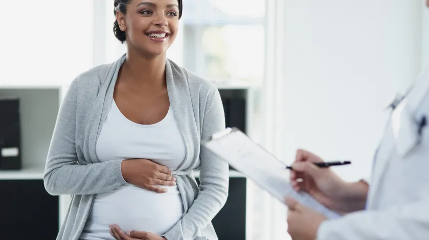 Pregnant woman holding her belly talking with doctor