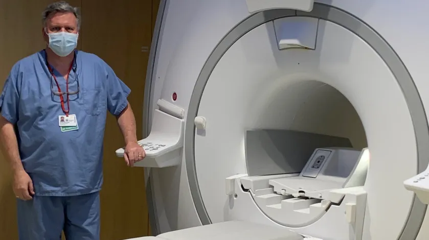 An MRI tech beside a new MRI machine