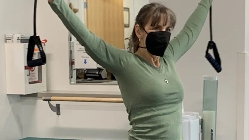 A woman using bands to stretch her arms in an exercise class