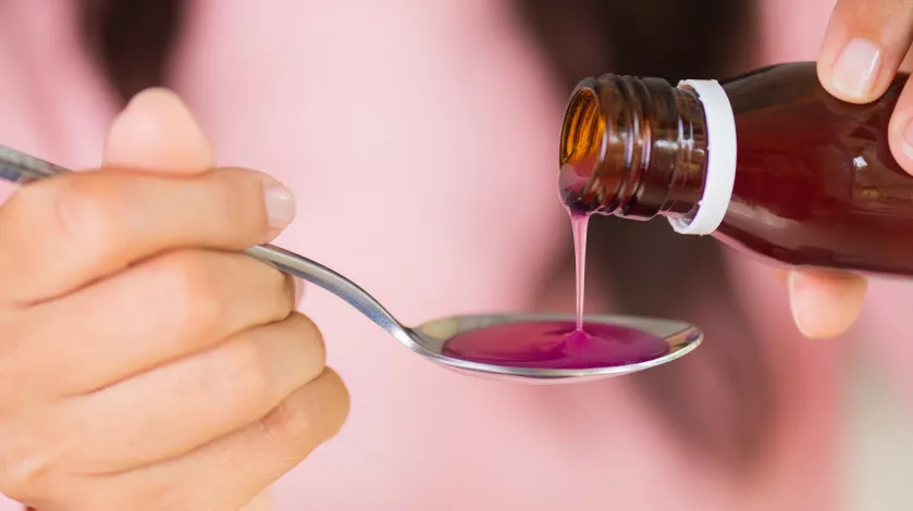 A woman pours children's medicine onto a spoon