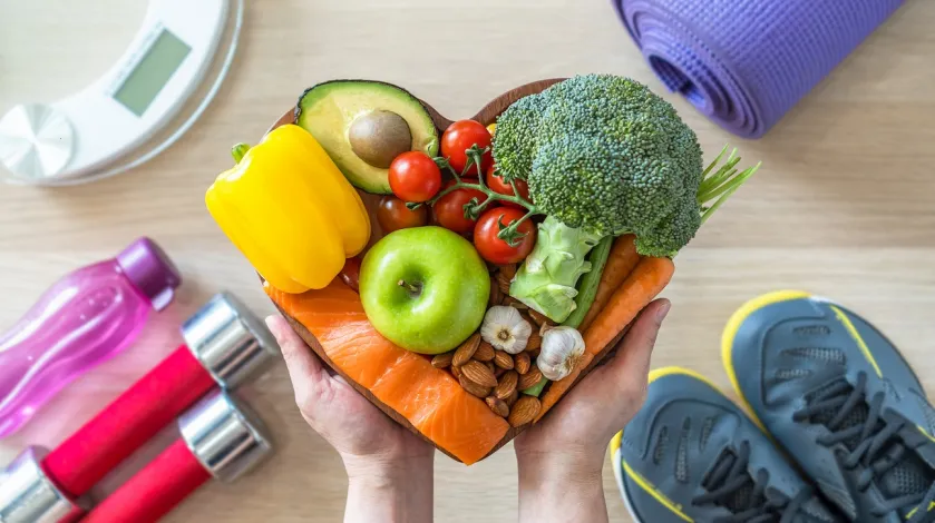 Heart shaped platter with healthy foods, running shoes, exercise equipment