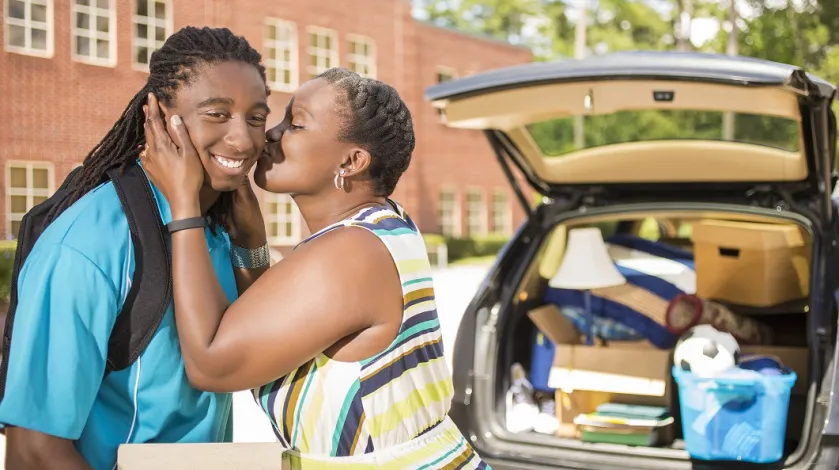 A Black woman kisses her son after dropping him off at college