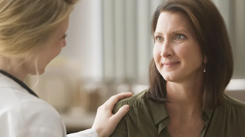 Female doctor comforts a middle aged female patient.