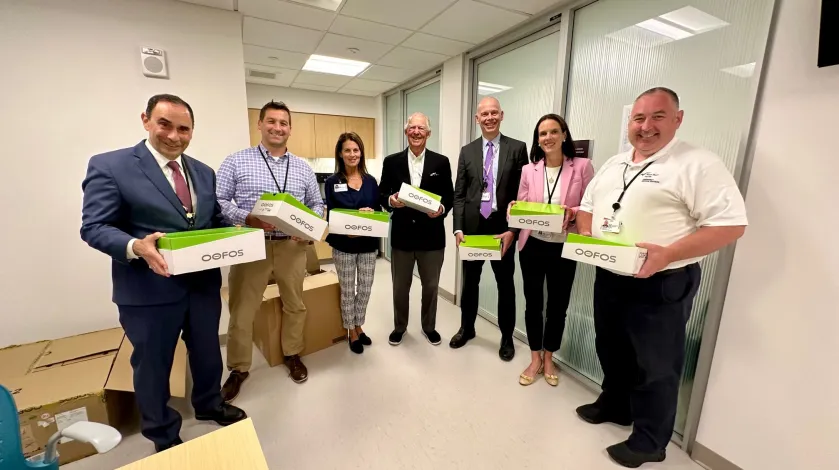 Allen Smith, MD and other South Shore Health leaders pose for a group photo with Tim Davis of Oofos