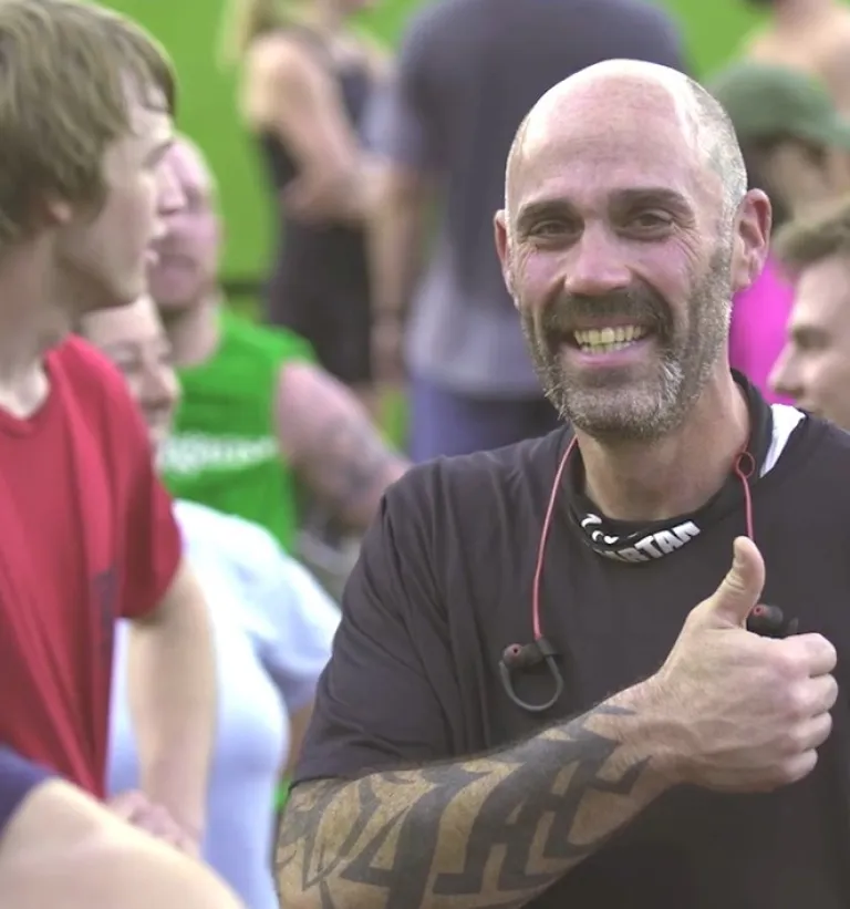 Mark P. smiles and gives a thumbs up to the camera after competing at a recent Spartan race