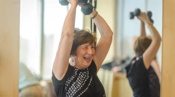 Older woman lifting weight above her head joyfully