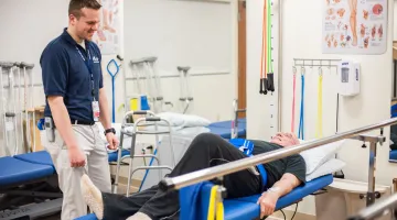 Man laying on a table and being assisted with exercises