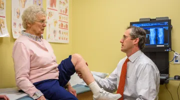 Doctor examining elderly woman's knee