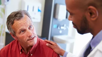 Doctor with hand on male patient's shoulder