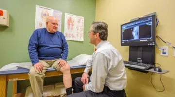 Doctor examining elderly man's knee