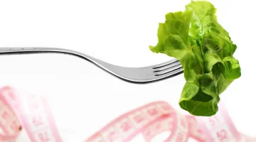 Lettuce on a fork with a tape measure in the background