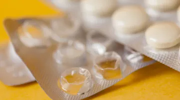 A close-up view of a pack of white heartburn medication pills inside of a silver blister pack