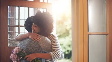 two women hugging in a sunny doorway