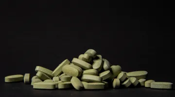 A pile of counterfeit prescription pills appears in front of a dark background