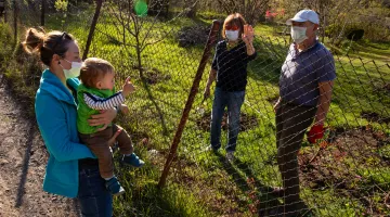 A young woman and a baby have a socially distant visit with an older couple