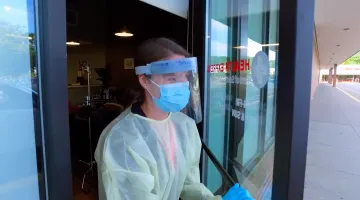 A health express employee in PPE provides carside triage