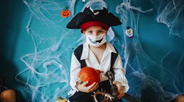 A child in a pirate costume with a face mask celebrates Halloween