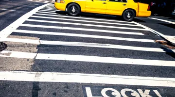 A city crosswalk with a sign that advises pedestrians to look