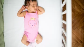 A top view of a baby asleep on her back in an empty crib for safe sleep