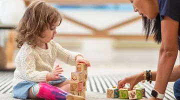 A young girl playing with blocks with an occupational therapist