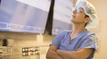 Doctor wearing scrubs looks up at screen