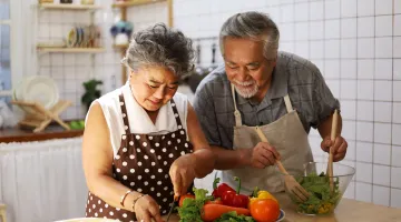 An older Asian couple prepares a healthy meal in their kitchen as part of diabetes nutrition management