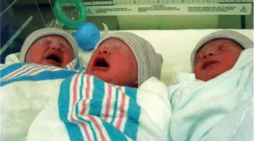 The Burgess triplets cry in a bassinet after being born in 2004