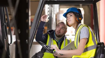 A forklift driver gets advice from her supervisor