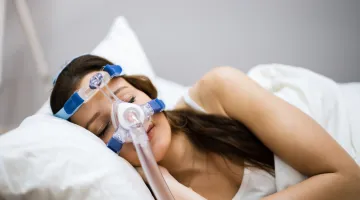 A woman sleeps while using a CPAP machine to help her breathing