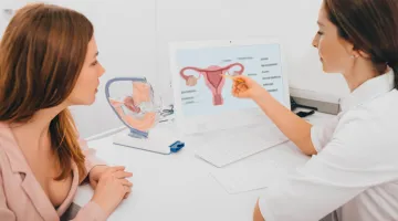 A woman watches as her doctor points to a diagram of a uterus for gynecologic cancer