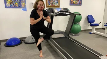 Woman in an exercise class balances on one foot in a yoga pose
