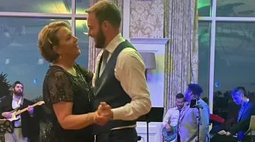 A woman dances with her son at his wedding