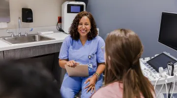A female nurse practitioner with female patient in an exam room