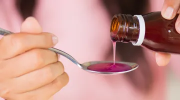 A woman pours children's medicine onto a spoon