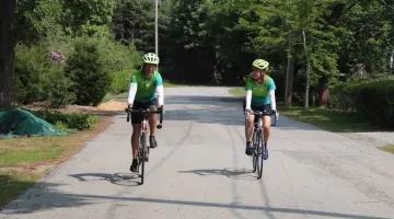 Len Bicknell and Laura Bicknell-Carbone ride their bikes side by side on a local road