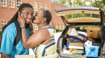 A Black woman kisses her son after dropping him off at college